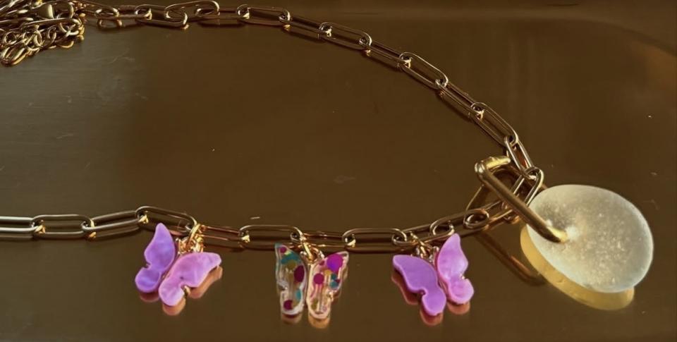 A custom piece of jewellery on a gold link chain, with pink butterflies. A custom piece of jewellery on a gold link chain, with pink butterflies.